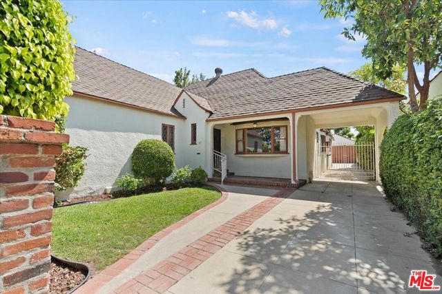 a front view of a house with a yard and potted plants