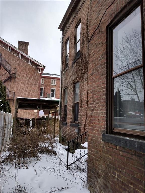 1005 Sheffield Street Pittsburgh, PA 15233 - Photo 3 of 25 a brick building with a bench in front of it