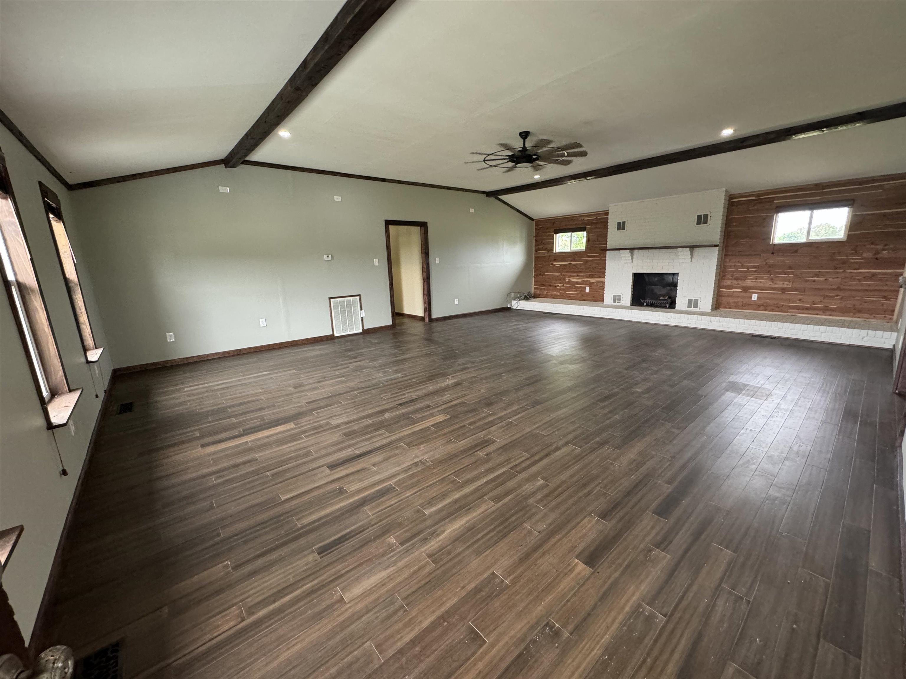 an empty room with wooden floor and windows