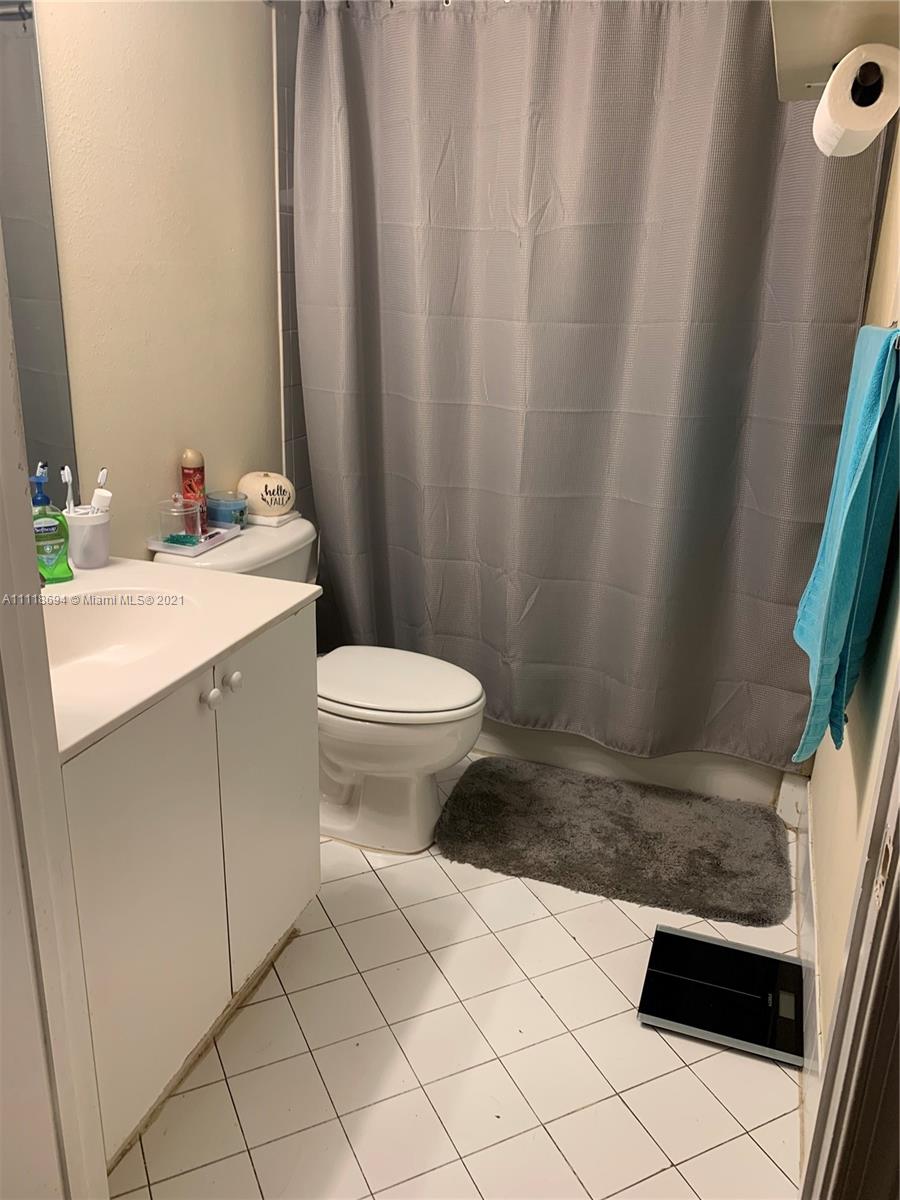 3770 North Jog Road, Unit 103 West Palm Beach, FL 33411 - Photo 8 of 15 a bathroom with a sink a toilet a mirror and shower curtain