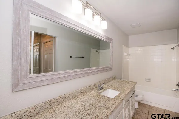 a bathroom with a granite countertop sink and a bathtub