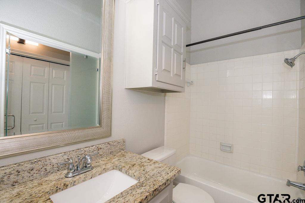 5809 Hollytree Drive Tyler, TX 75703 - Photo 21 of 32 a bathroom with a granite countertop bathtub shower sink and toilet