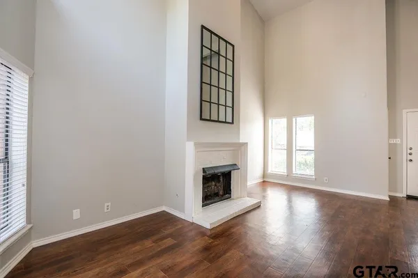 an empty room with windows and fireplace