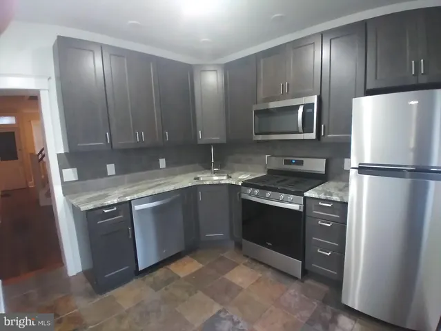 a kitchen with stainless steel appliances granite countertop a refrigerator stove and sink