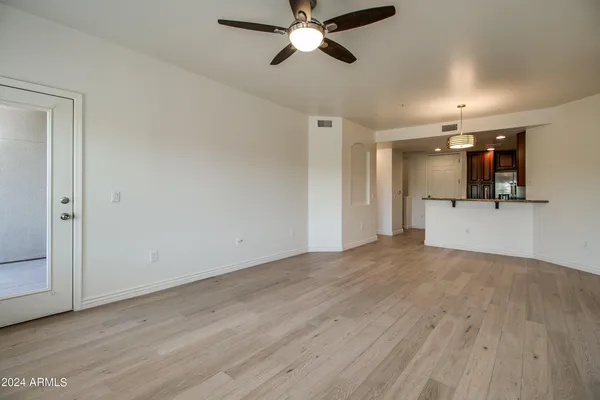 a view of empty room with wooden floor and ceiling fan