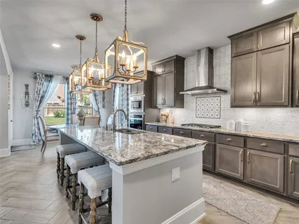 a kitchen with stainless steel appliances granite countertop a sink a stove and a wooden floors