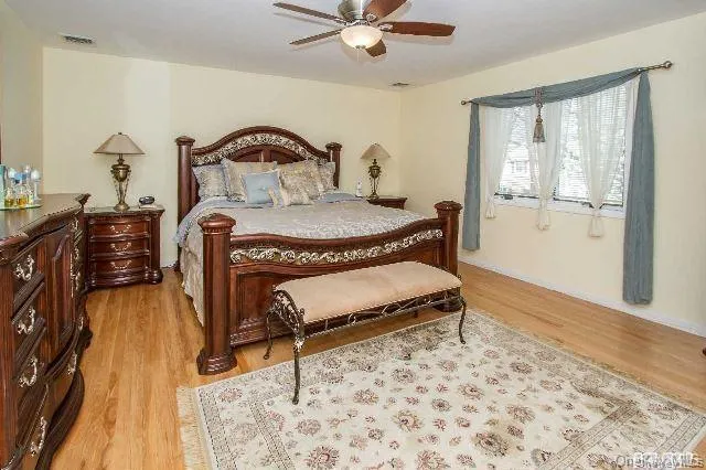 a bedroom with a bed and a dresser with wooden floor