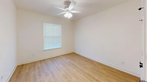 an empty room with a window and a ceiling fan