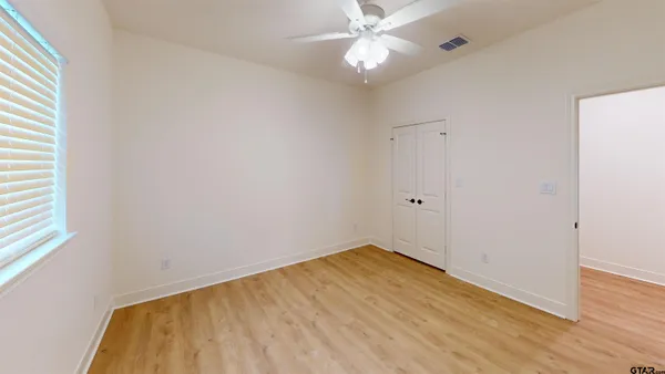 an empty room with wooden floor and fan