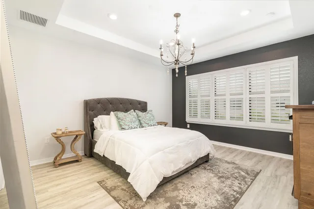 a spacious bedroom with a large bed and a chandelier