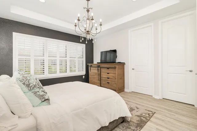 a bedroom with a large bed and a flat tv screen on dresser