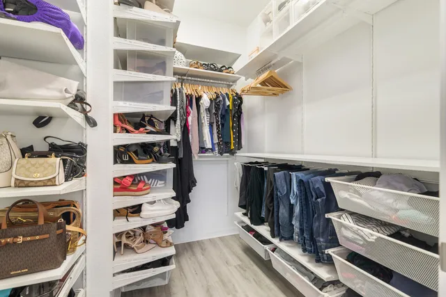 a view of walk in closet with clothes and shoes