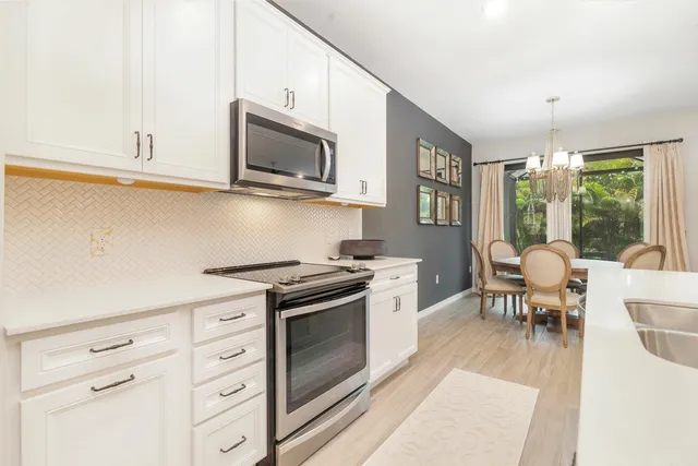 a kitchen with stainless steel appliances granite countertop a stove a sink dishwasher and a microwave oven with white cabinets