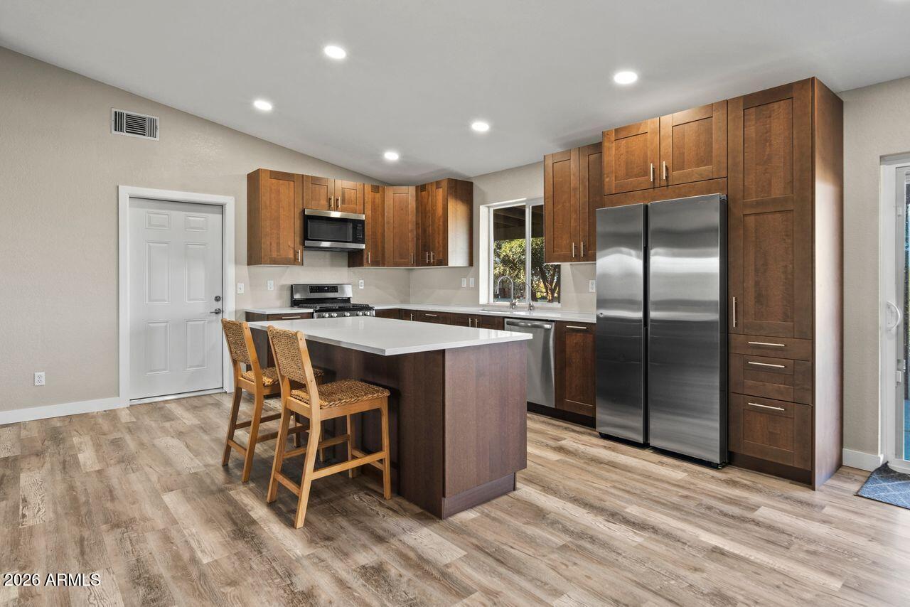 51718 West Donald Road Aguila, AZ 85320 - Photo 8 of 59 a kitchen with stainless steel appliances granite countertop a stove a refrigerator a microwave a oven with white cabinets and wooden floor