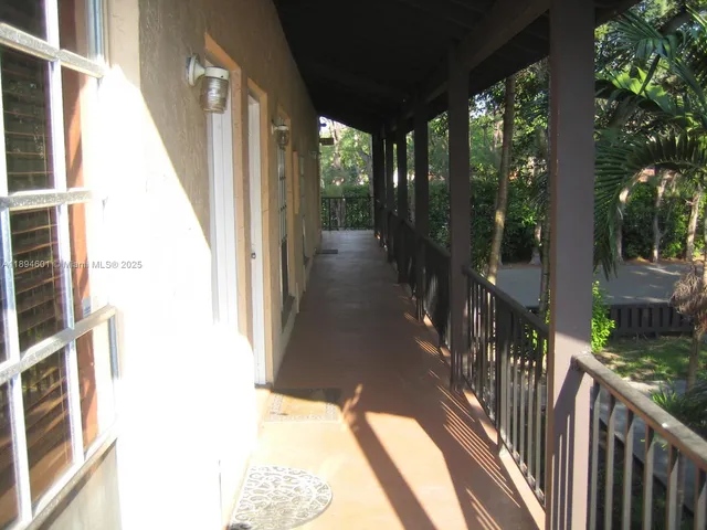 a view of a house with a small yard plants and a large tree