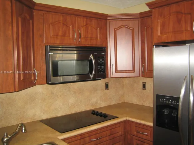 a kitchen with granite countertop wood cabinets stainless steel appliances and a refrigerator