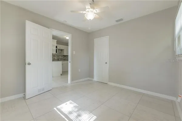an empty room with closet and a chandelier fan