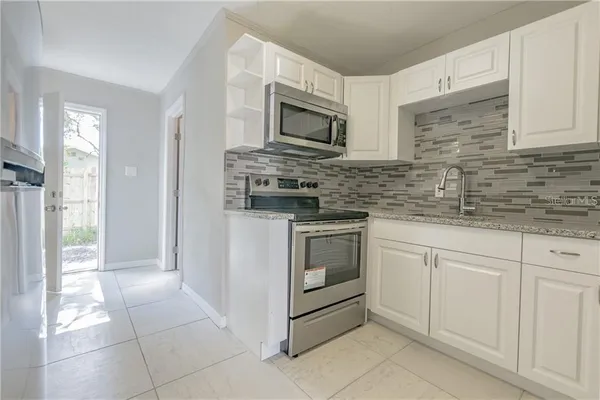 a kitchen with granite countertop white cabinets stainless steel appliances and a sink