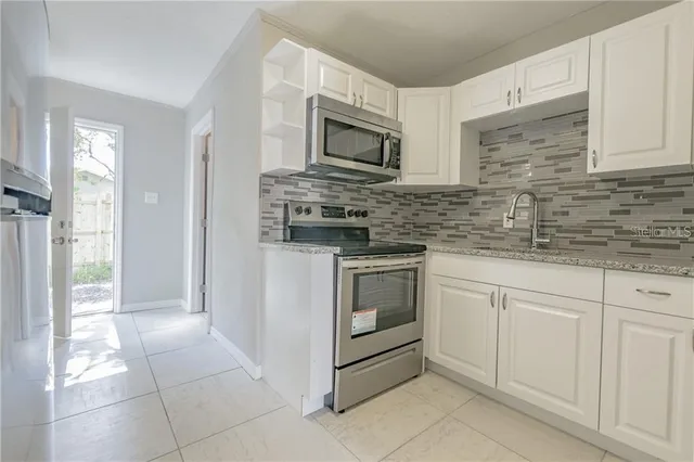 a kitchen with granite countertop white cabinets stainless steel appliances and a sink