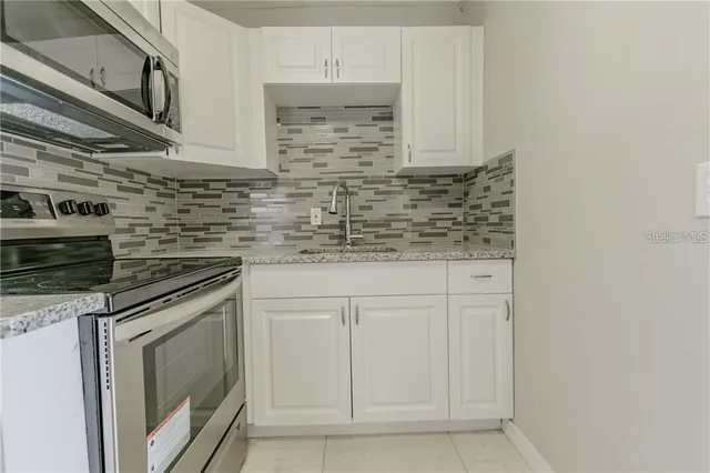 a kitchen with stainless steel appliances granite countertop white cabinets and a stove
