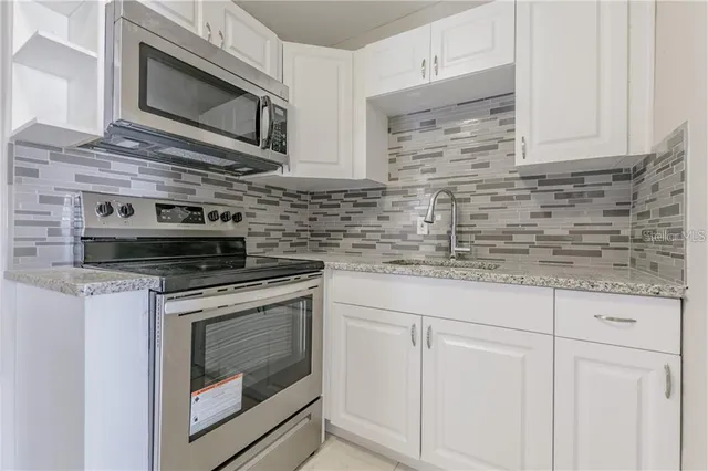 a kitchen with stainless steel appliances granite countertop white cabinets stove top oven and microwave
