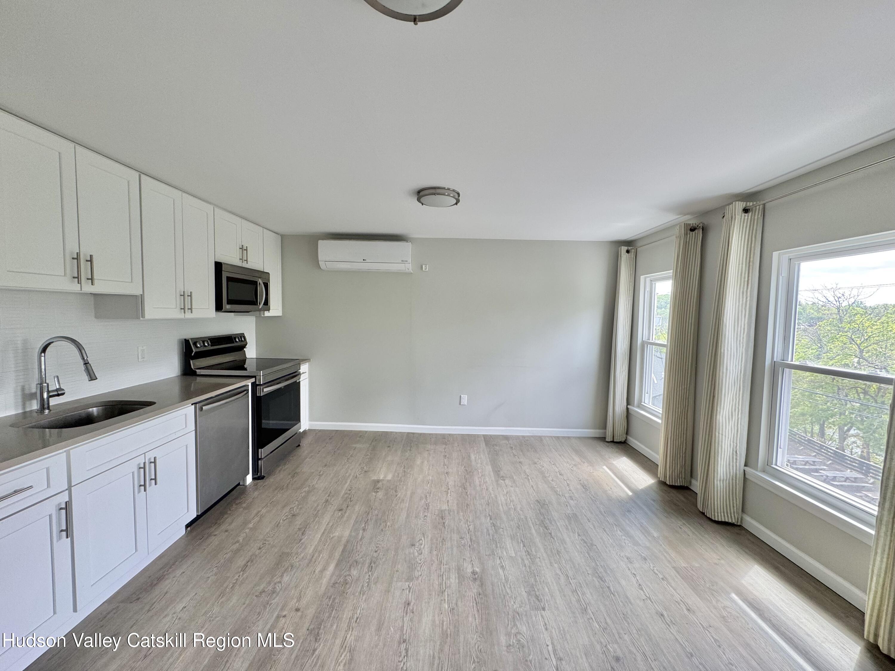 218 Water Street, Unit 5 Catskill, NY 12414 - Photo 5 of 12 a kitchen with granite countertop a stove top oven sink and cabinets