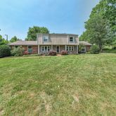 a view of a house with a big yard and large trees