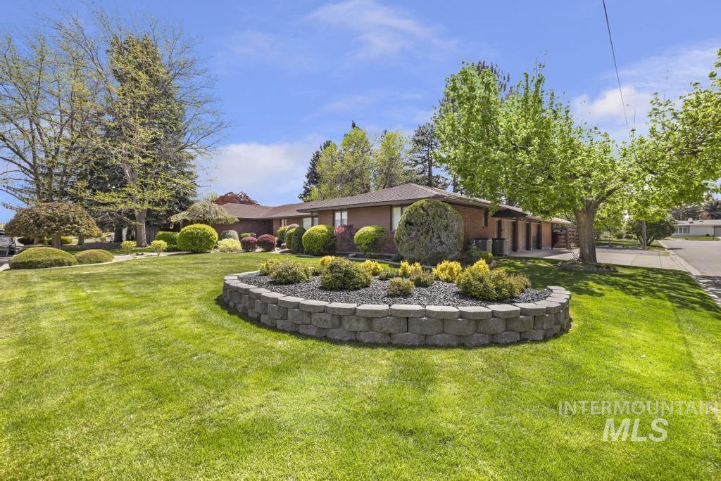 2018 Rancho Vista Drive Twin Falls, ID 83301 - Photo 5 of 50 Expansive front yard featuring a manicured lawn, established trees, and a decorative retaining wall with plantings