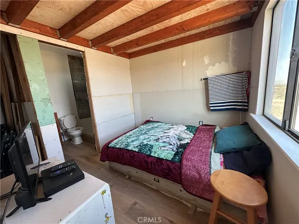 a bedroom with a bed and a flat tv screen on the dresser