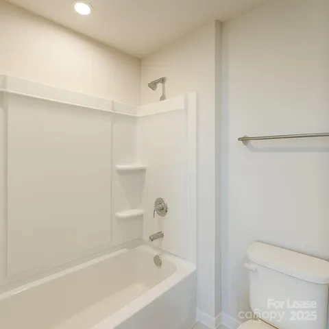 a white bath tub sitting next to a white toilet and vanity