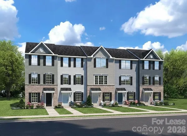 a front view of a building with street that has lawn chairs and a large tree
