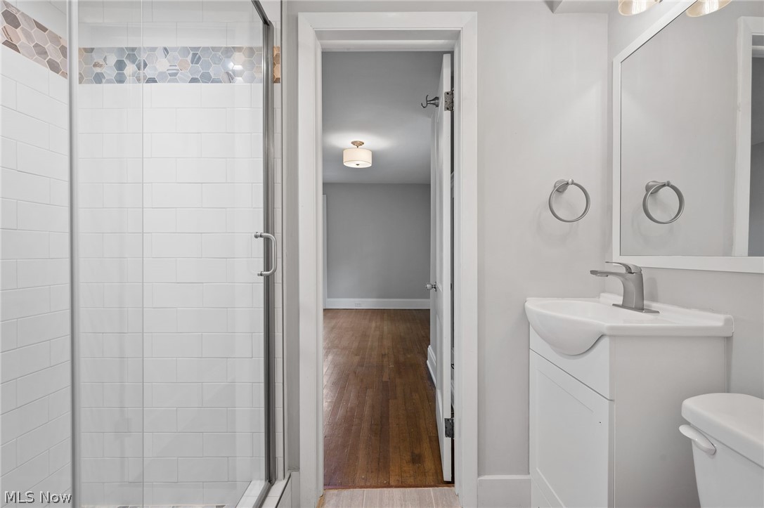2924 Brighton Road Shaker Heights, OH 44120 - Photo 18 of 31 Full bath featuring a shower stall, vanity, toilet, baseboards, and wood finished floors