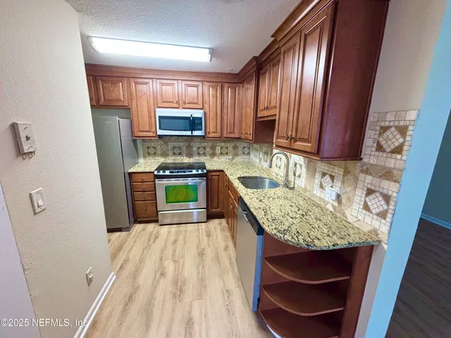 a kitchen with stainless steel appliances granite countertop a sink stove and refrigerator