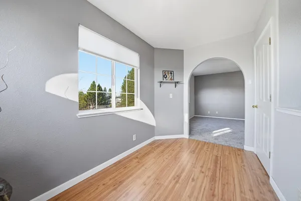 a view of empty room with wooden floor and fan