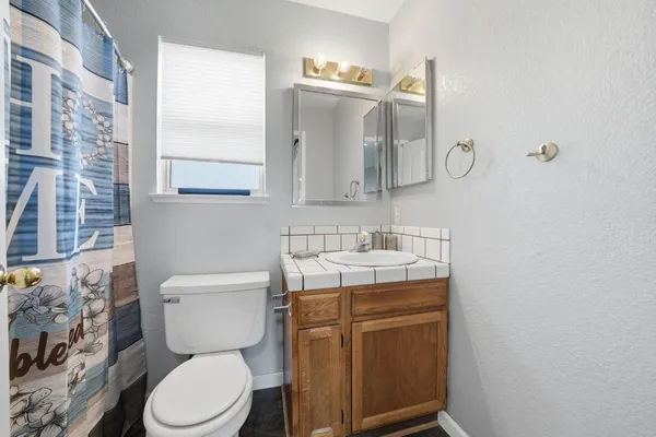 a bathroom with a granite countertop toilet sink and mirror