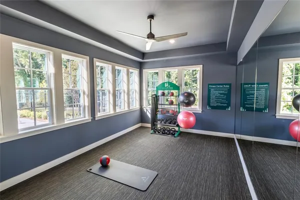 a living room with furniture floor to ceiling window hardwood floor and a ceiling fan