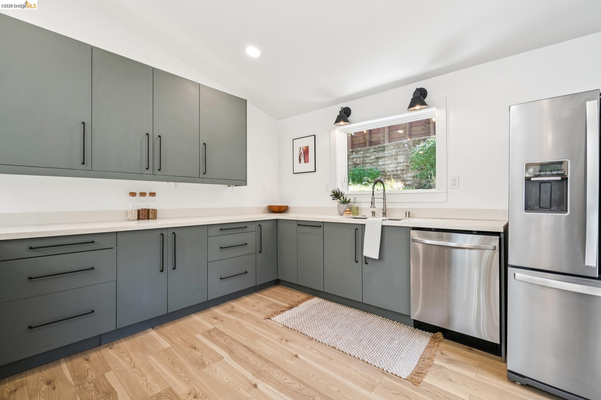 6400 Pinehaven Road Oakland, CA 94611 - Photo 24 of 78 Kitchen featuring light wood-finish flooring, grey cabinetry with black hardware, white countertops, and stainless steel appliances
