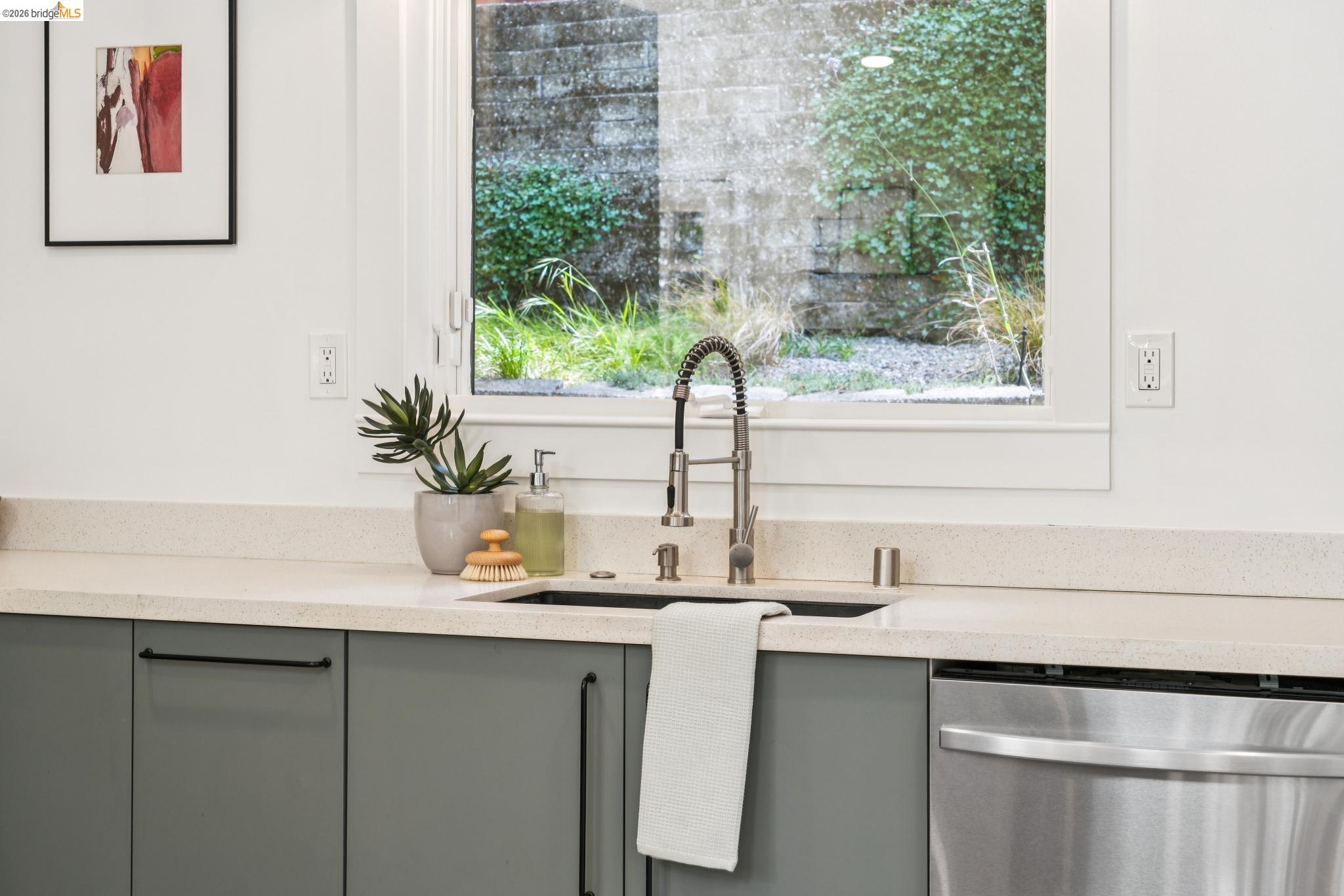 6400 Pinehaven Road Oakland, CA 94611 - Photo 25 of 78 Kitchen sink area featuring a large window, light-colored countertops, gray cabinetry with dark hardware, a stainless steel pull-down faucet, and an integrated stainless steel appliance