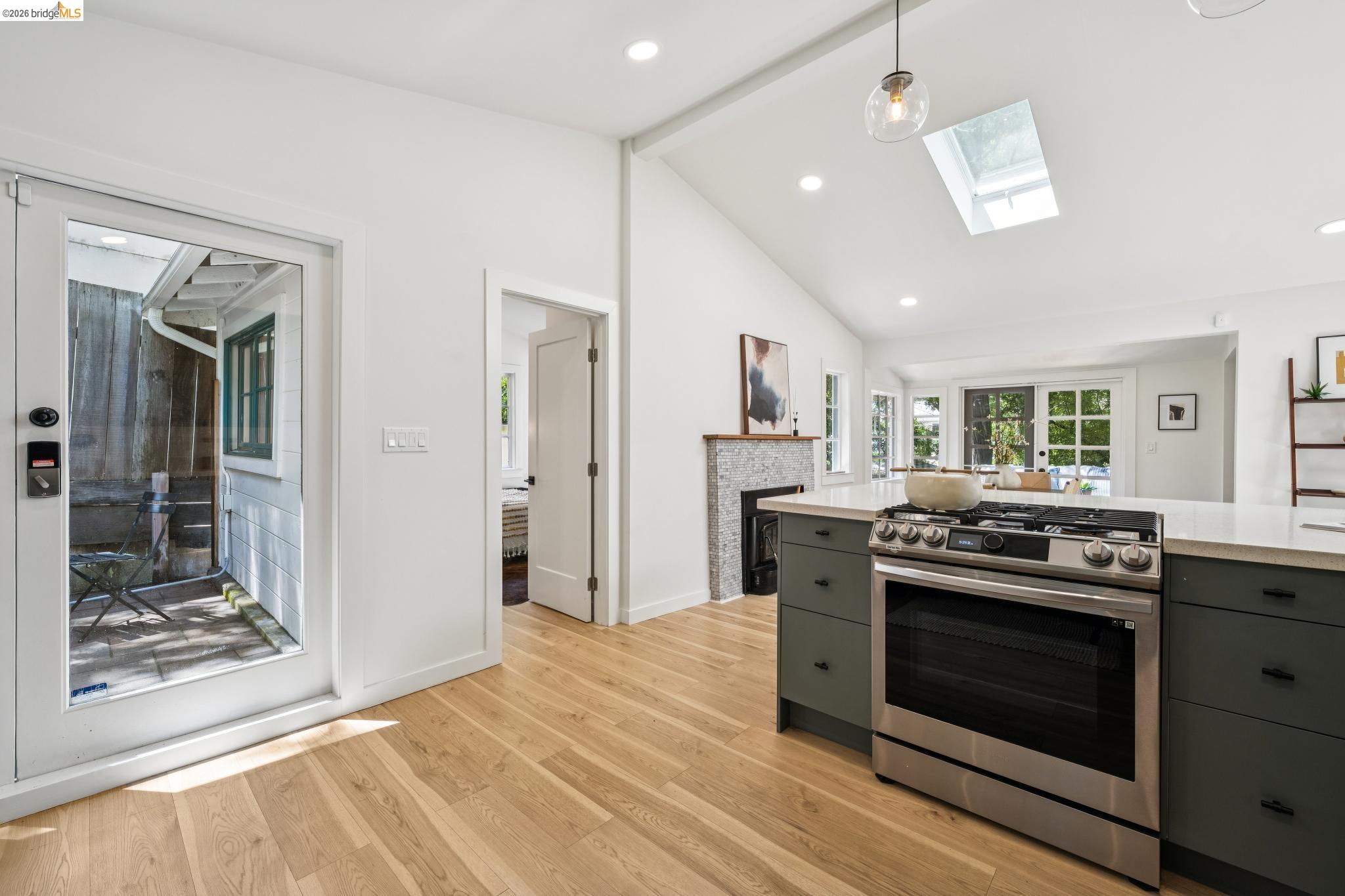6400 Pinehaven Road Oakland, CA 94611 - Photo 29 of 78 Kitchen featuring vaulted ceilings, wood-finish flooring, a skylight, and a stainless steel gas range