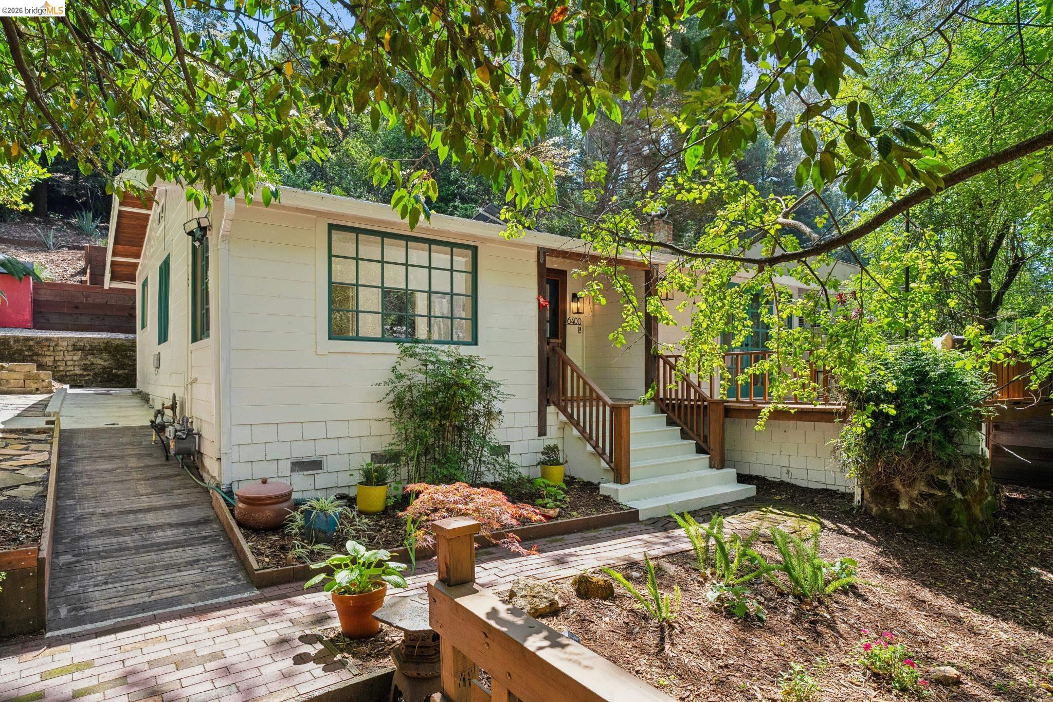 6400 Pinehaven Road Oakland, CA 94611 - Photo 3 of 78 White exterior siding with green trim, featuring a wood deck and porch with matching wood railings