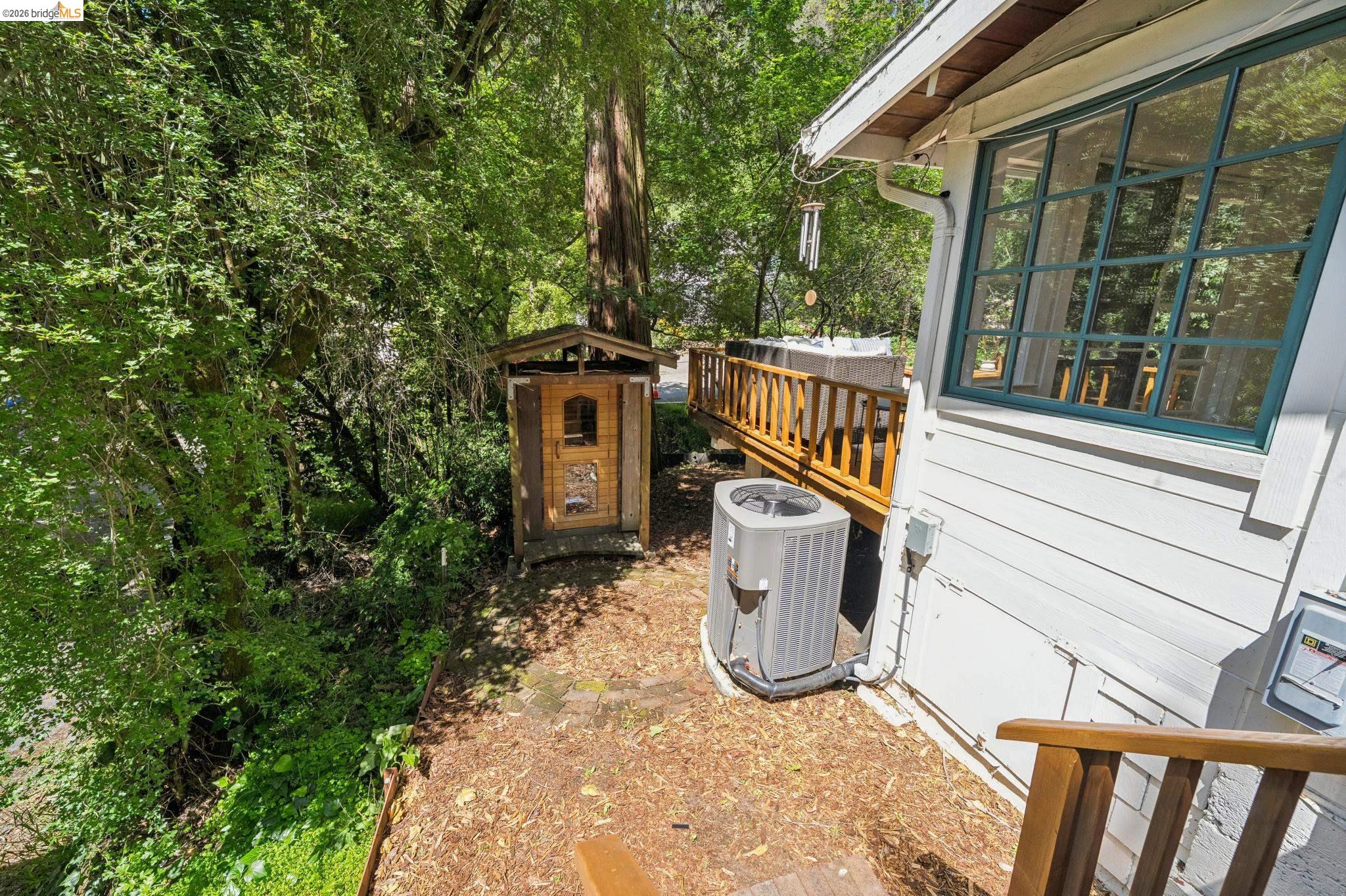 6400 Pinehaven Road Oakland, CA 94611 - Photo 37 of 78 Rear exterior featuring a wood-decked patio with a wooden railing, white horizontal siding, and a prominent multi-pane window with green trim