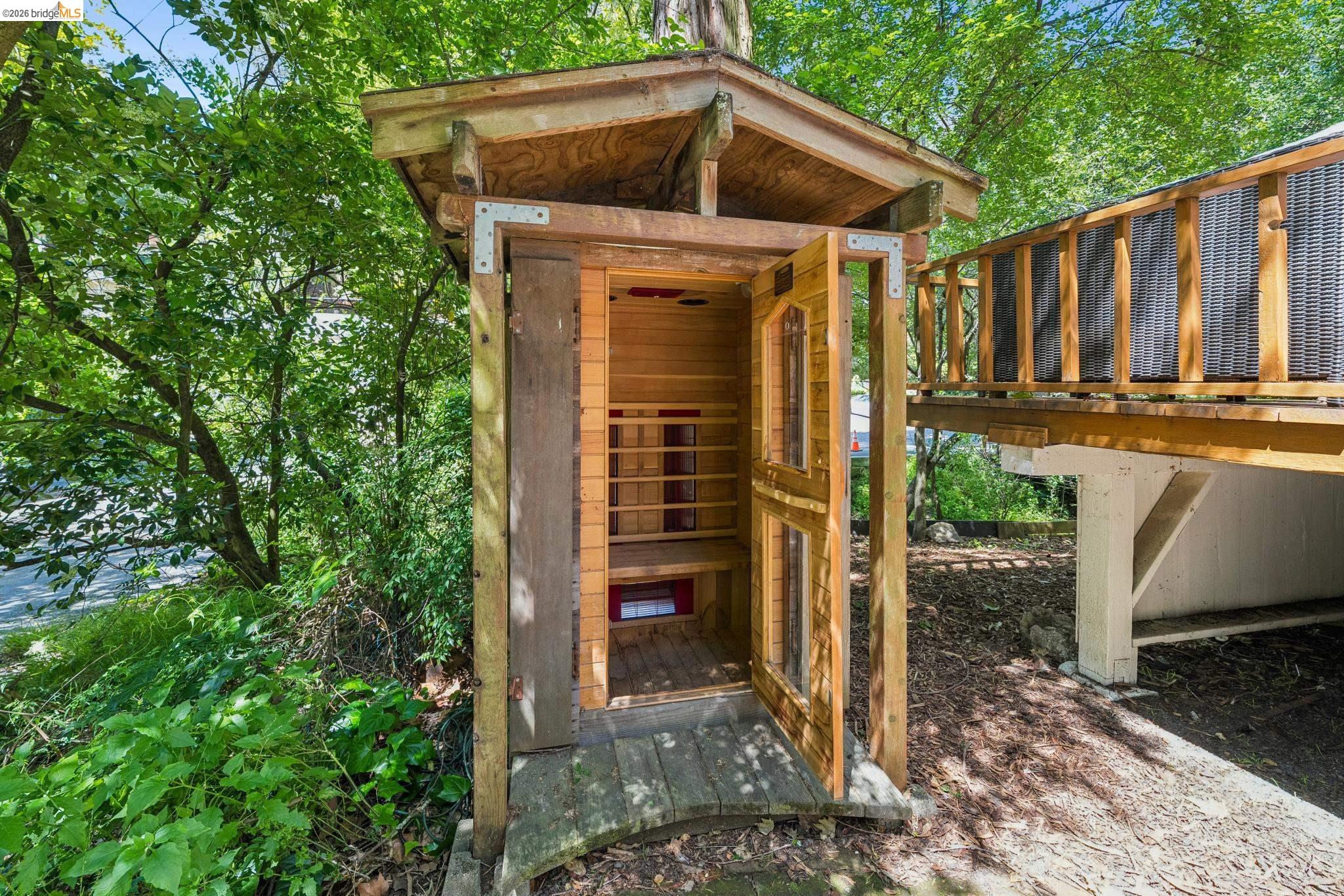 6400 Pinehaven Road Oakland, CA 94611 - Photo 38 of 78 Freestanding wood-clad structure with an open slatted door and an elevated wood deck featuring a lattice-style railing