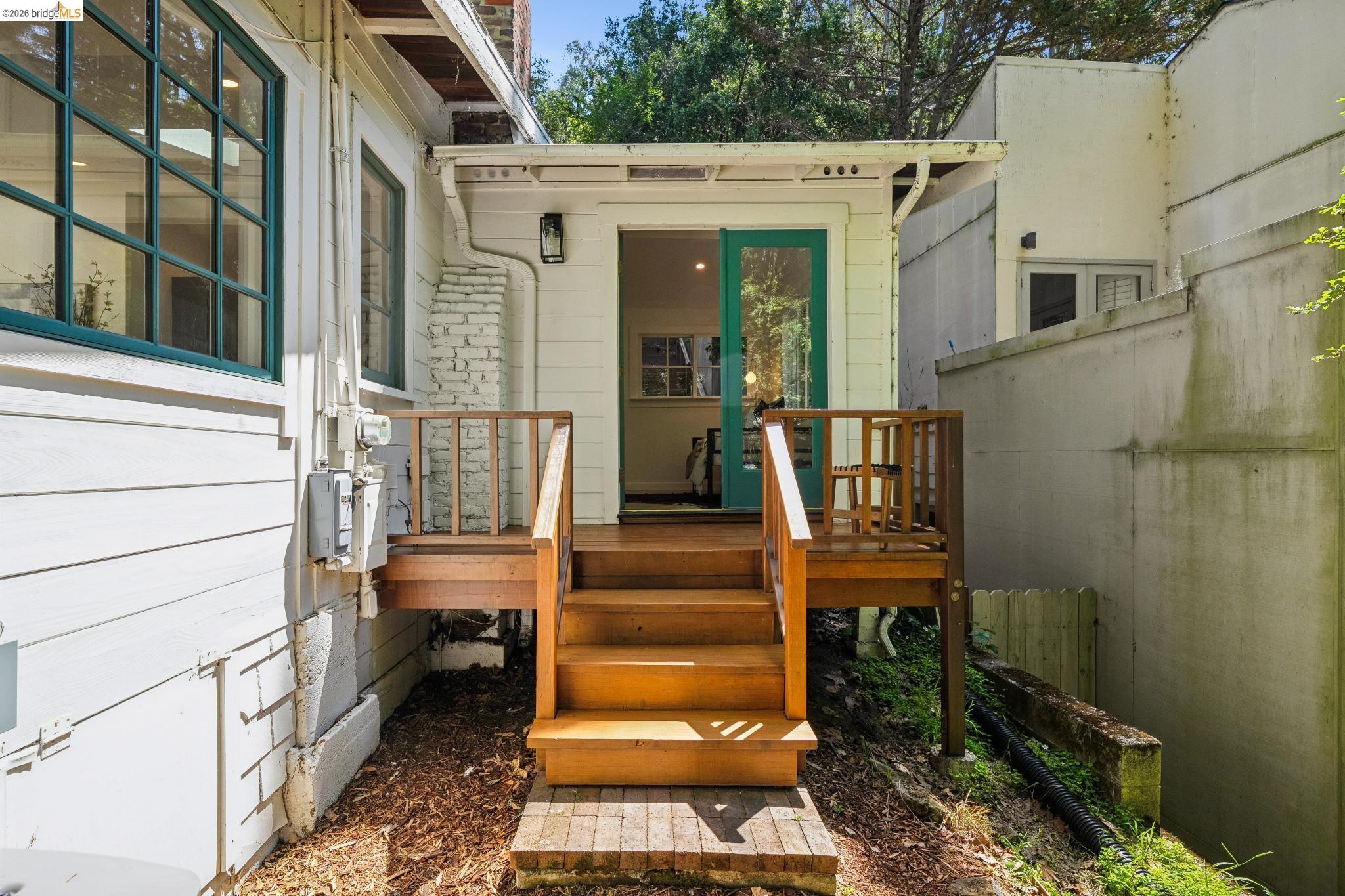 6400 Pinehaven Road Oakland, CA 94611 - Photo 39 of 78 Exterior deck with wooden railings leading to an entry featuring a vibrant teal door