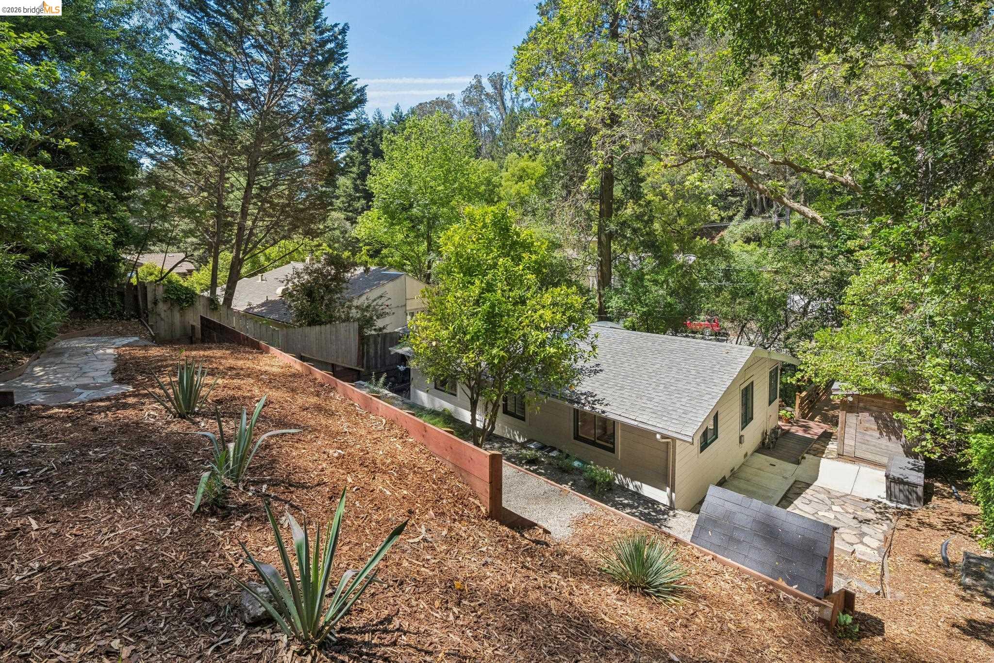 6400 Pinehaven Road Oakland, CA 94611 - Photo 50 of 78 Sloped outdoor area featuring wood chip ground cover, agave plantings, and a retaining wall