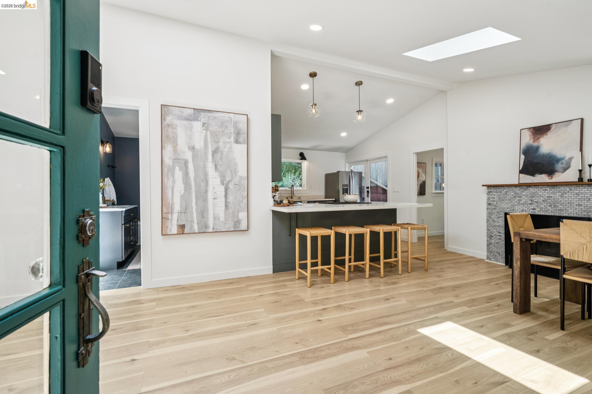 6400 Pinehaven Road Oakland, CA 94611 - Photo 5 of 78 Open concept living area featuring light wood-finish flooring, a kitchen island with seating, a fireplace with a mosaic tile surround, and a skylight