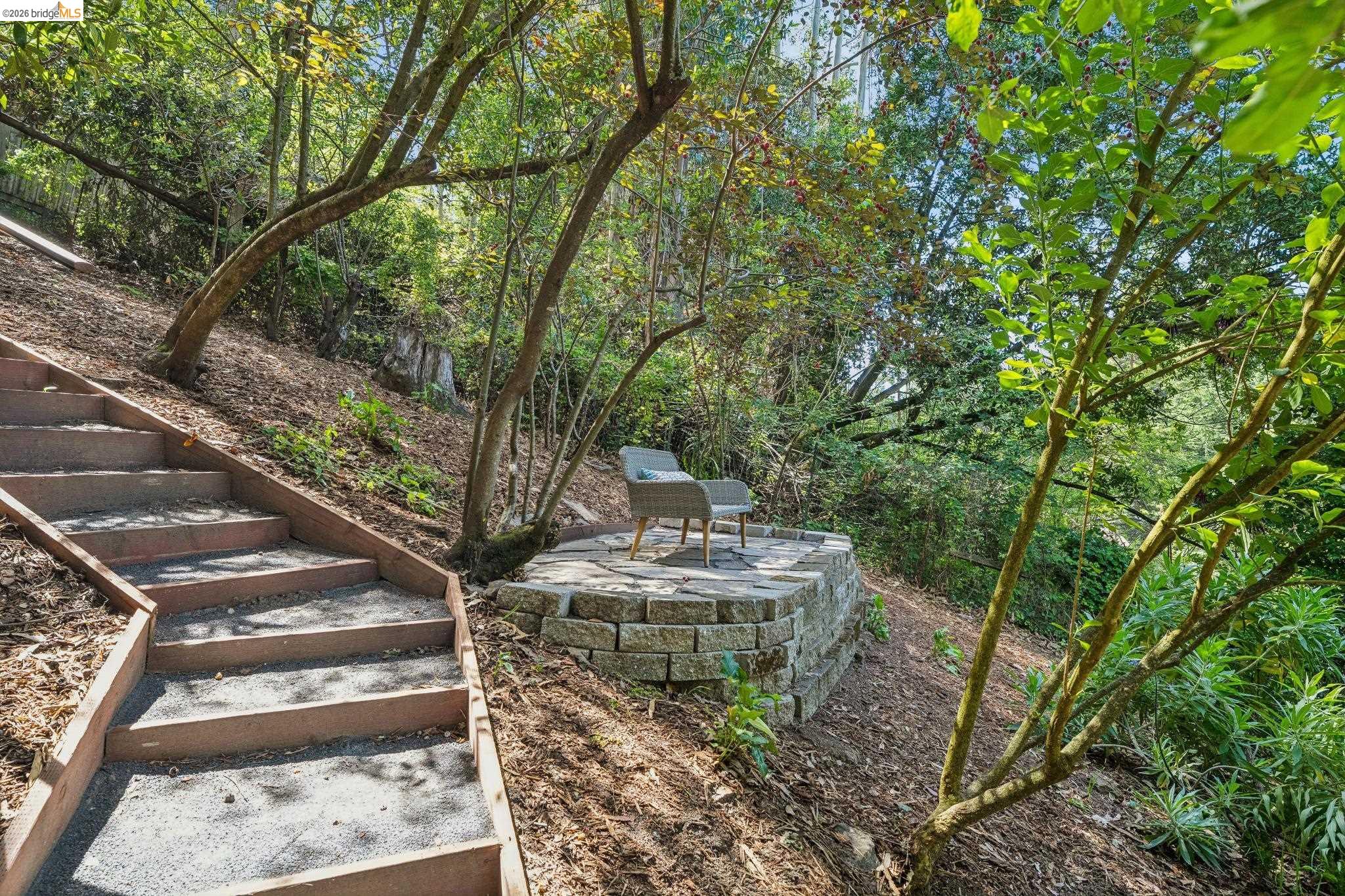 6400 Pinehaven Road Oakland, CA 94611 - Photo 53 of 78 Terraced backyard featuring wood and gravel steps, a stone block retaining wall, and a paved patio area