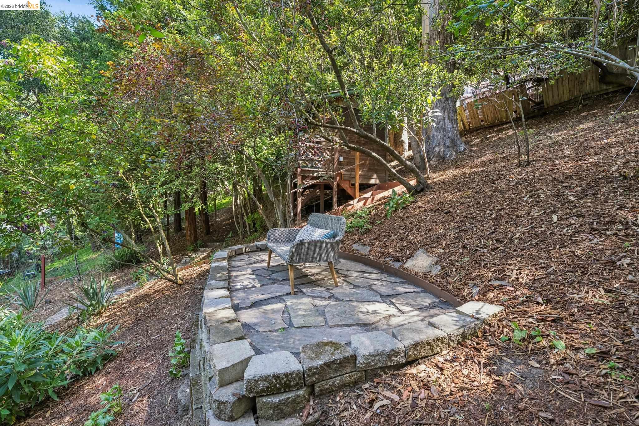 6400 Pinehaven Road Oakland, CA 94611 - Photo 54 of 78 Stone-paved patio area with a natural stone retaining wall, surrounded by mature trees and natural landscaping