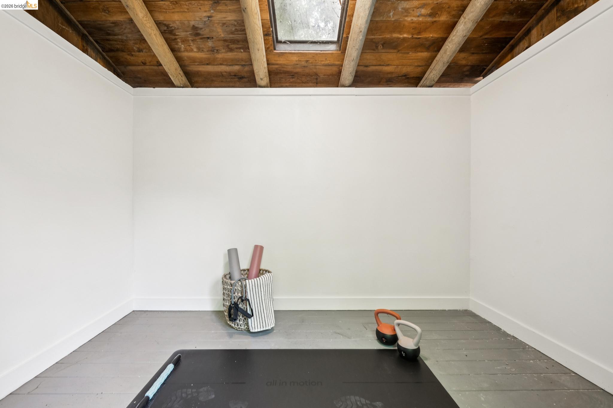 6400 Pinehaven Road Oakland, CA 94611 - Photo 59 of 78 Interior room featuring exposed wood beam ceiling with a skylight, white painted walls, white baseboards, and painted wood flooring