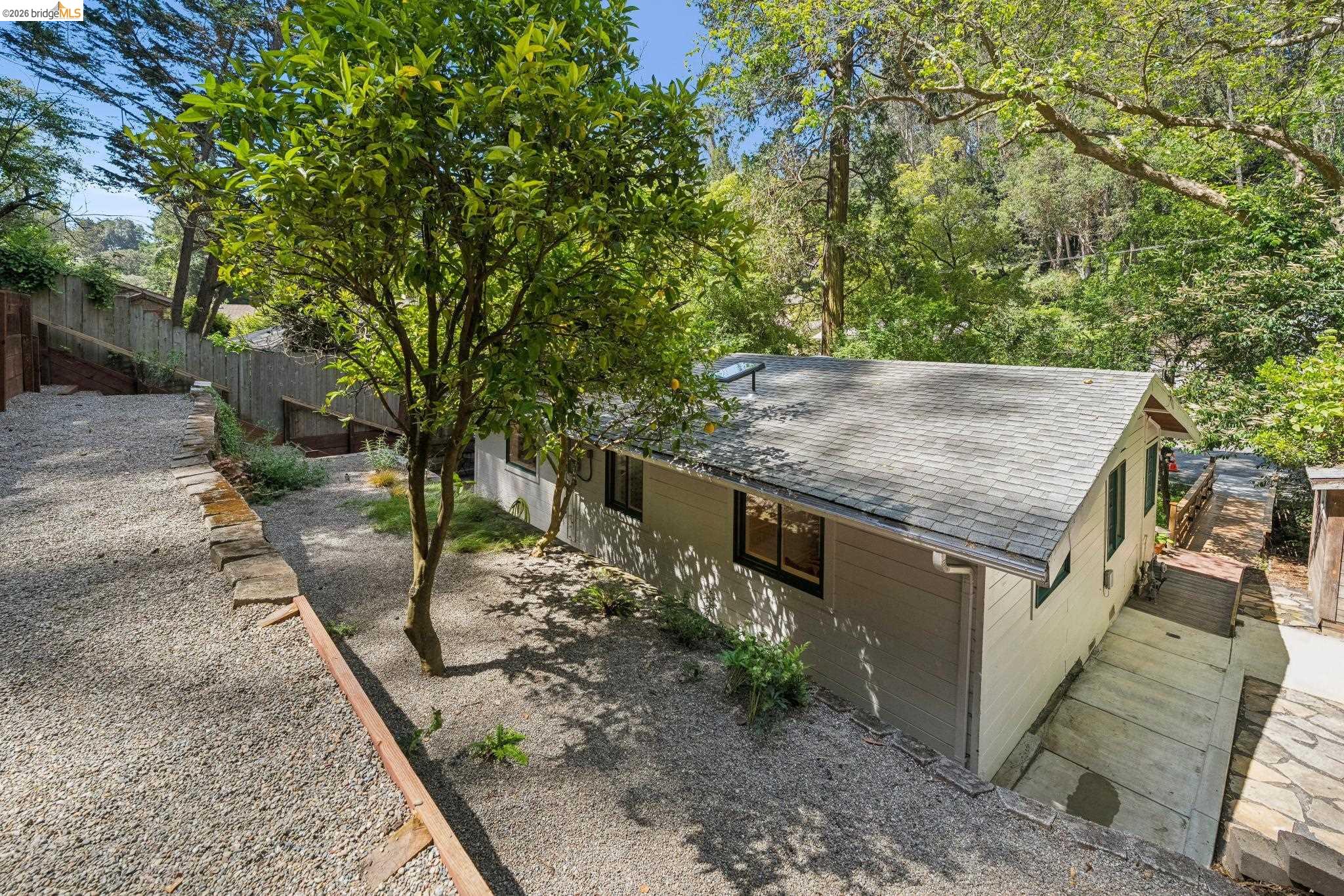 6400 Pinehaven Road Oakland, CA 94611 - Photo 63 of 78 Exterior featuring a light-colored façade, dark window trim, an asphalt shingle roof, and a gravel driveway