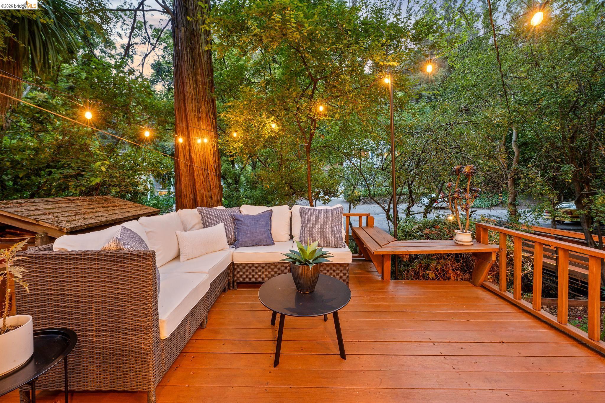 6400 Pinehaven Road Oakland, CA 94611 - Photo 68 of 78 Spacious wood-finish deck with built-in railing, integrated wooden bench, and string lighting